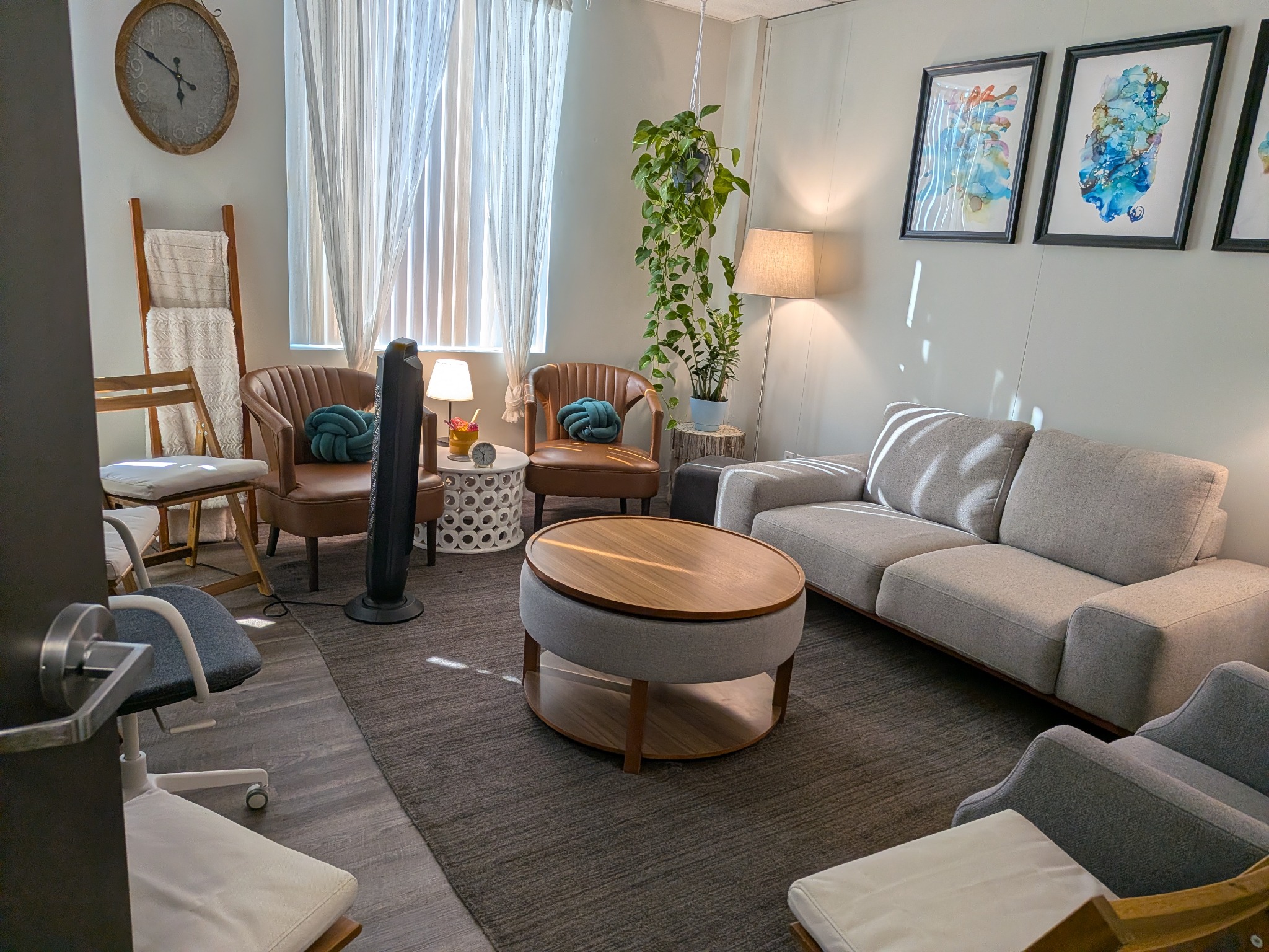 Spacious therapy room with a sofa, armchairs, plants, and natural light